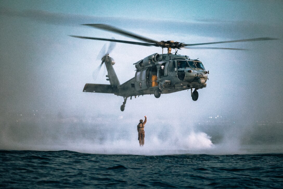 A U.S. Marine with the Maritime Raid Force, 11th Marine Expeditionary Unit, leaps out of a U.S. Navy MH-60S Seahawk with Helicopter Sea Combat Squadron (HSC) 21 during helocast training at Marine Corps Base Camp Pendleton, California, Sept. 18, 2025. Helocasting is an airborne technique that enables Marines to insert into a body of water from an aircraft. (U.S. Marine Corps photo by Cpl. Joseph Helms)