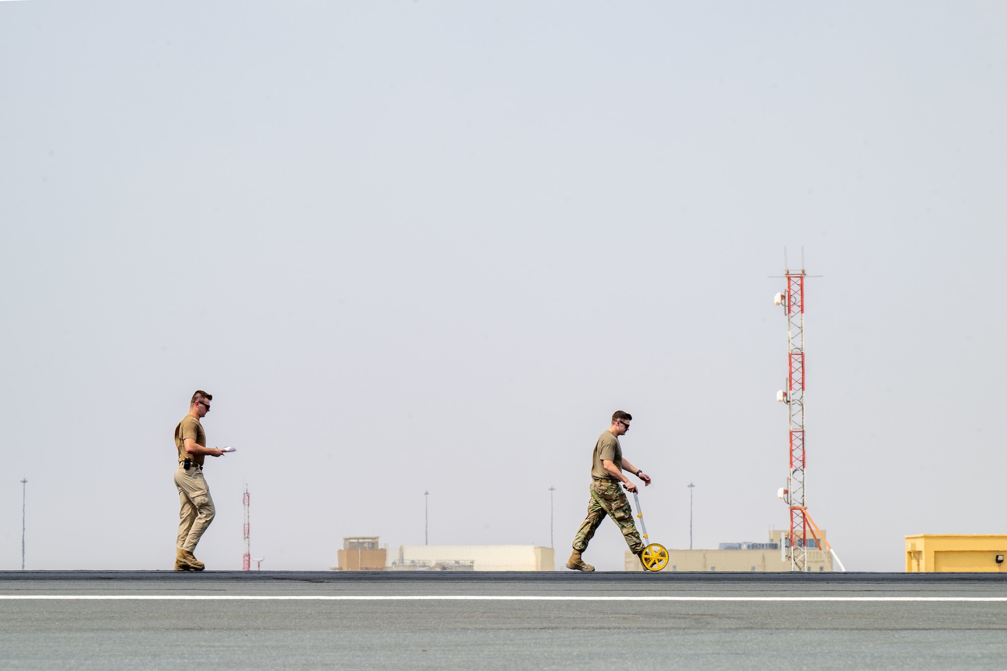 U.S. Air Force Staff Sgt. Joseph Clower, left, and Staff Sgt. Hunter Ricketts, 379th Expeditionary Civil Engineer Squadron barrier maintenance technicians, take measurements after an aircraft arresting system test within the U.S. Central Command area of responsibility, Sept. 14, 2025. The test followed a 10-year overhaul of the system, completed through a joint effort by the 379th ECES Barrier Maintenance and Heavy Equipment sections. (U.S. Air Force photo by Senior Airman Amanda Jett)