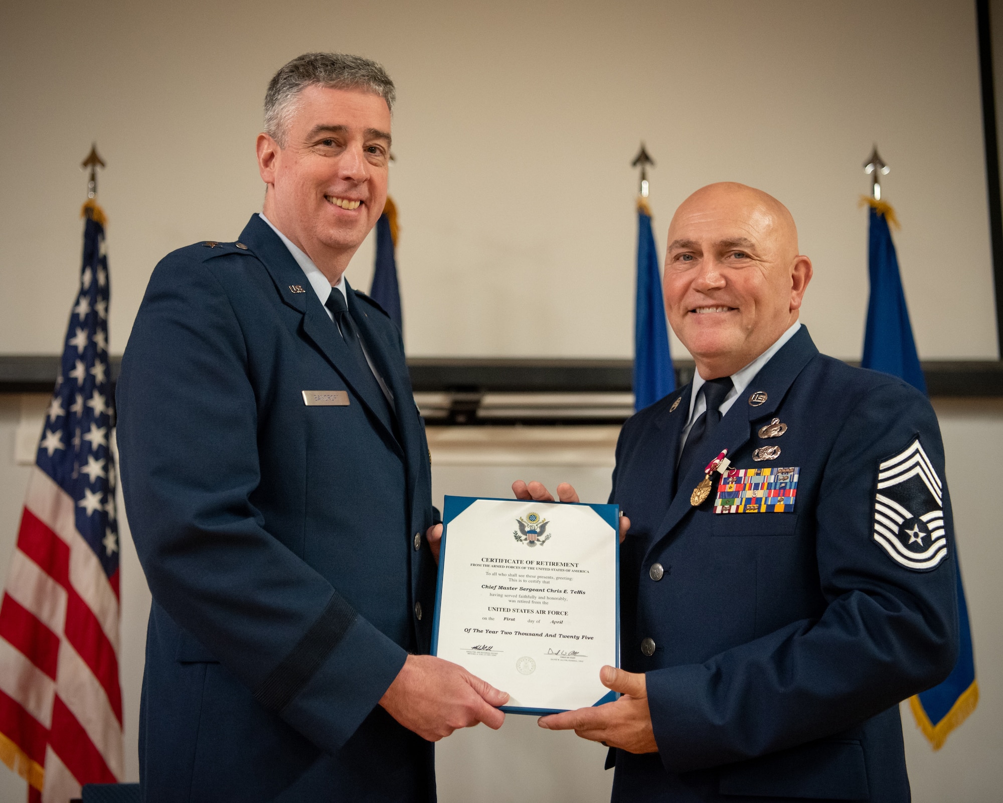 Chief Master Sgt. Chris Tellis, right, outgoing senior enlisted leader for the 123rd Contingency Response Group, receives his certificate of retirement from Brig. Gen. Bruce Bancroft, Kentucky’s adjutant general for Air, during Tellis’ retirement ceremony at the Kentucky Air National Guard Base in Louisville Ky., June 7, 2025. Tells is retiring after 38 years of military service. (U.S. Air National Guard photo by Master Sgt. Joshua Horton)