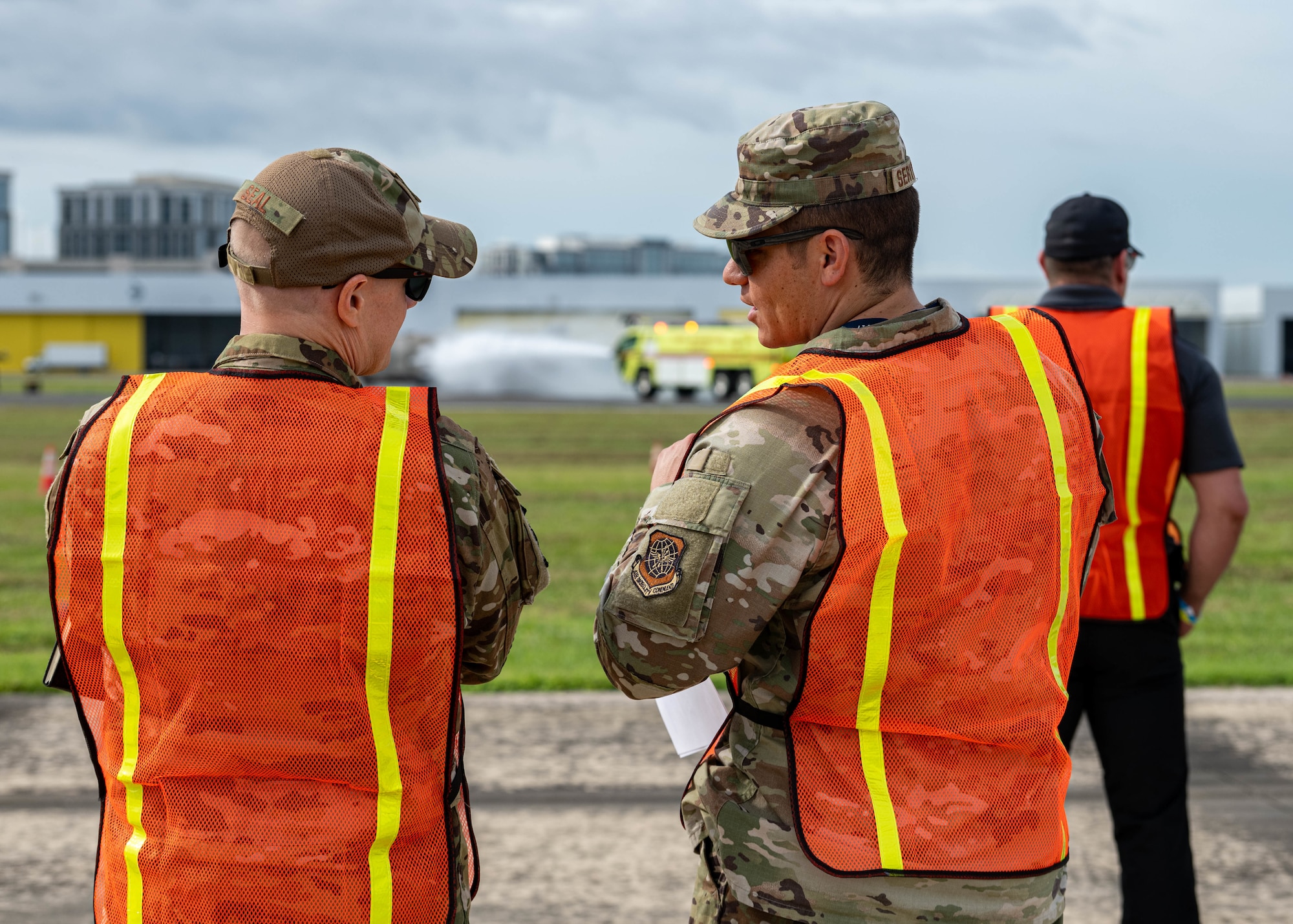 U.S. Air Force Lt. Col. Paul Seal, 6th Air Refueling Wing chief of safety, left, and Tech. Sgt. Adam Serdynski, 6th ARW flight safety non-commissioned officer, right, observe flight line firefighting operations during the 2025 Triennial "Double Trouble" emergency response exercise at Tampa International Airport, Sept. 17, 2025. The team provided safety oversight alongside civilian agencies during a simulated aircraft emergency. (U.S. Air Force photo by Airman 1st Class Monique Stober)