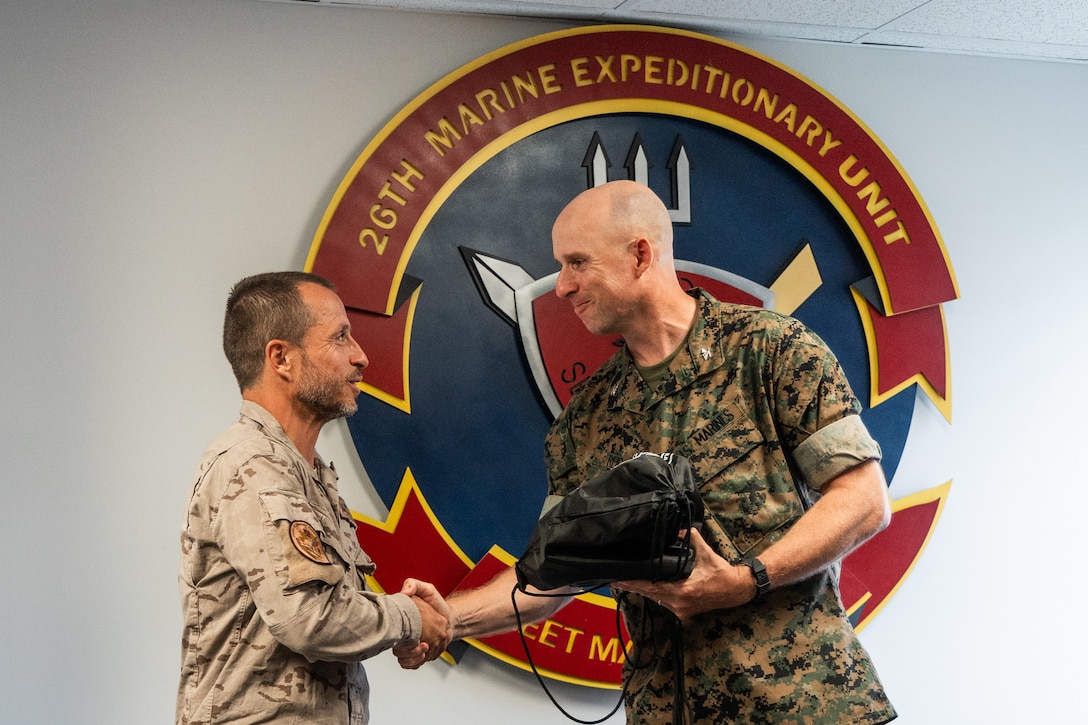 U.S. Marine Corps Col. Ben Reid, right, the commanding officer of the 26th Marine Expeditionary Unit, presents a gift to Teniente Coronel Emerito Pablo Alvarez Leon, a battalion commander with Infantería de Marina (Spanish marine corps) during exercise UNITAS 2025 at Marine Corps Base Camp Lejeune, Sept. 27, 2025. UNITAS, which is Latin for “unity,” was conceived in 1959 and has taken place annually since first conducted in 1960. This marks the 66th iteration of the world’s longest running annual multinational maritime exercise. (U.S. Marine Corps photo by Cpl. Osmar VasquezHernandez)