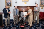 Joe Thomason (center), former U.S. Naval Research Laboratory (NRL) senior staff engineer, receives a certificate from Capt. Randy Cruz (center-right), NRL commanding officer, recognizing his 62 years of service in Washington, D.C., Sept. 9, 2025. Thomason’s contributions advanced NRL’s capabilities in high-frequency skywave radar, target detection, and long-range surveillance. (U.S. Navy photo by Sarah Peterson)