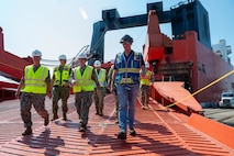 A group of people walk out of a cargo ship.
