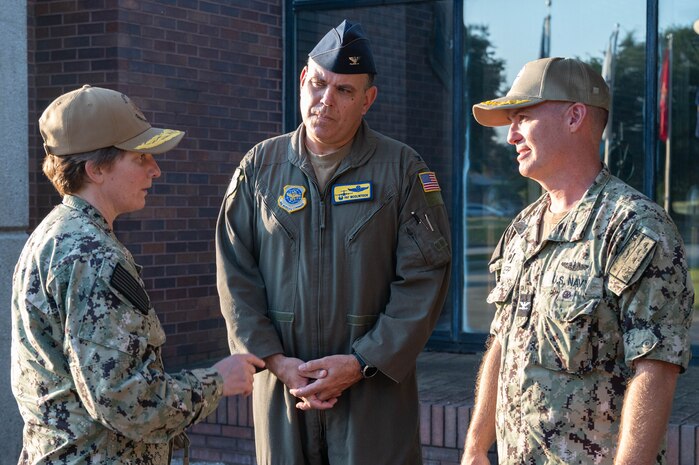 Three members of leadership have a conversation outside of a building.