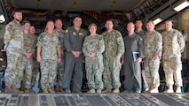 A group of leaders stand for a group photo inside of a C-17 Globemaster III at the end of a base tour