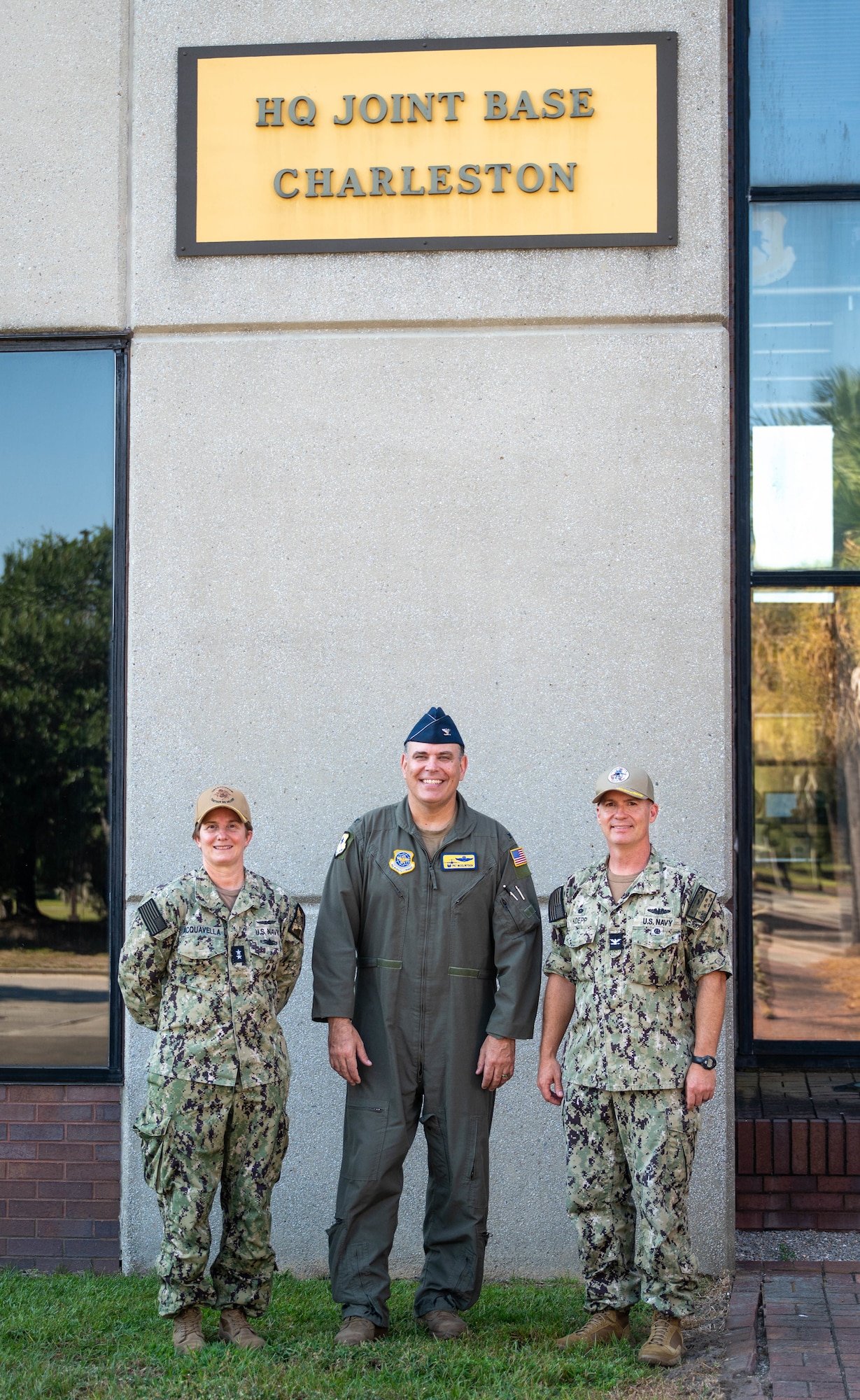 Leadership stands for a photo beneath a sign reading 'HQ Joint Base Charleston.'