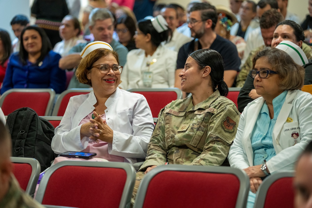 Image of three people sitting in a crowd.