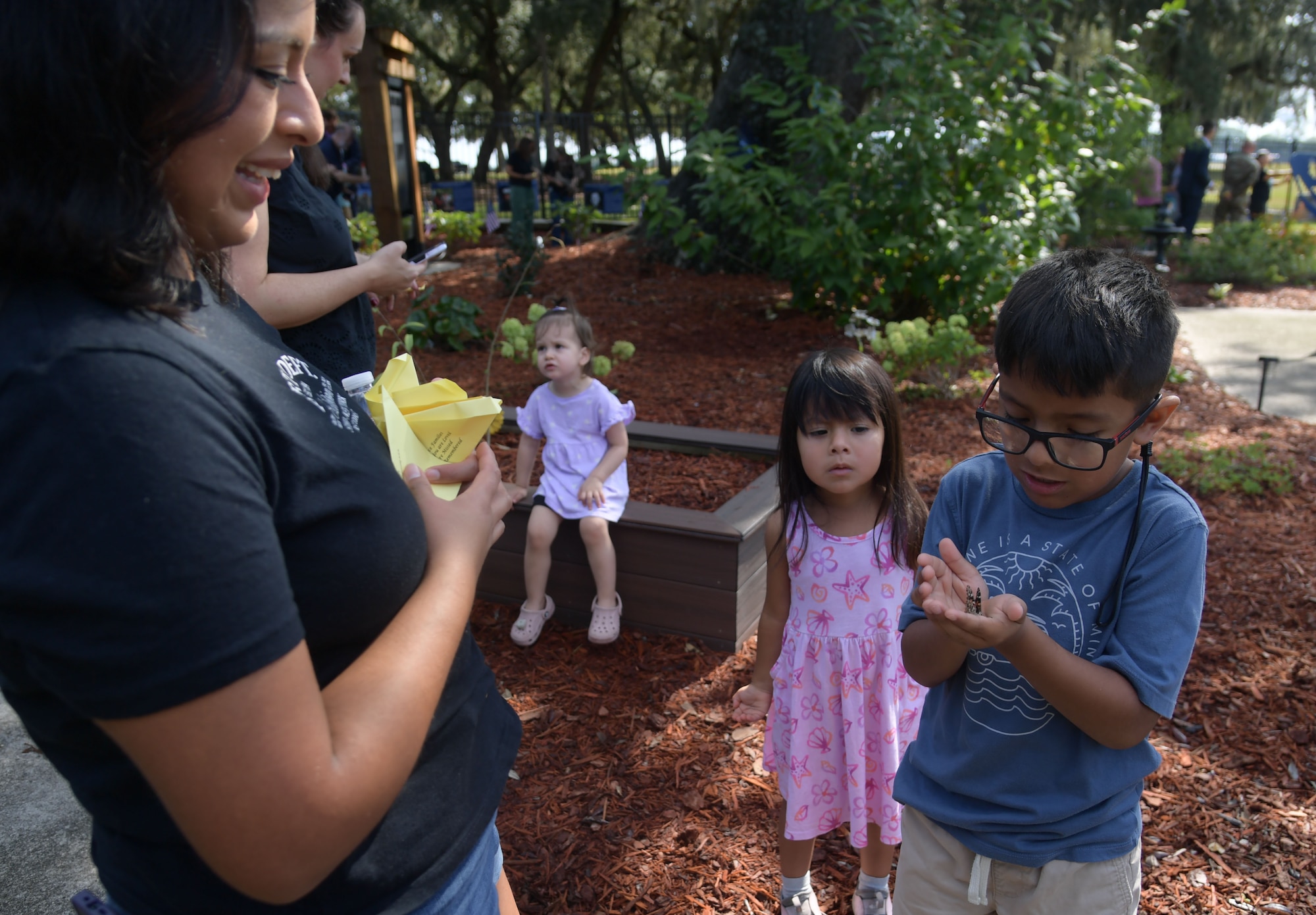 A family gather as a little boy holds a butterfly in his hand.