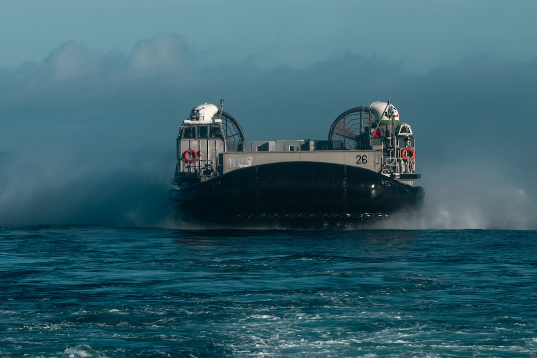 An inflated landing craft with two fans on the back moves on the ocean during the day, as seen from head-on.