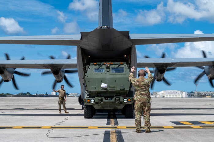 U.S. Air Force Tech. Sgt. Trevor Humes, 36th Airlift Squadron instructor loadmaster, guides a U.S. Marine Corps High Mobility Artillery Rocket System into a C-130J Super Hercules assigned to the 36th AS during a HIMARS Rapid Insertion training at Kadena Air Base, Japan, Sept. 18, 2025. The training gave personnel an opportunity to practice emerging tactics, techniques, and procedures that allow C-130 aircrews to reload ammo pods into a HIMARS without any material handling equipment, such as K-loaders and forklifts, in a process known as HIMARS Direct Reload Inside Plane. This marked the first time on record that a Mobility Air Force aircrew within Pacific Air Forces has executed HIDRIP, as the 36th AS continues to develop homegrown training events designed to refine the skills needed to support operations in austere environments. (U.S. Air Force photo by Staff Sgt. Natalie Doan)