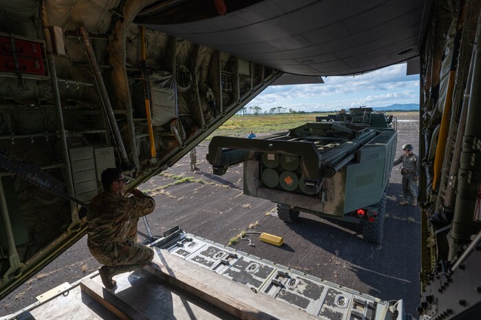 U.S. Air Force Senior Airman Christian Hubbard, 36th Airlift Squadron instructor loadmaster, guides a U.S. Marine Corps High Mobility Artillery Rocket System out of a C-130J Super Hercules during a HIMARS Rapid Insertion training at Japan Air Self-Defense Force Kenebetsu Air Base, Japan, Sept. 19, 2025. The training gave personnel an opportunity to practice emerging tactics, techniques, and procedures that allow C-130 aircrews to reload ammo pods into a HIMARS without any material handling equipment, such as K-loaders and forklifts, in a process known as HIMARS Direct Reload Inside Plane. This marked the first time on record that a Mobility Air Force aircrew within Pacific Air Forces has executed HIDRIP, as the 36th AS continues to develop homegrown training events designed to refine the skills needed to support operations in austere environments. (U.S. Air Force photo by Staff Sgt. Natalie Doan)