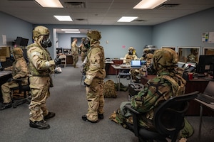 U.S. Air Force Airmen assigned to the 23rd Air Task Force and 723rd Combat Air Base Squadron, wear mission-oriented protective posture level four gear while working in the operations center during a field training exercise at the Silver Flag Exercise Site on Tyndall Air Force Base, Fla., Sept. 18, 2025. The Airmen donned protective gear during a simulated chemical attack.