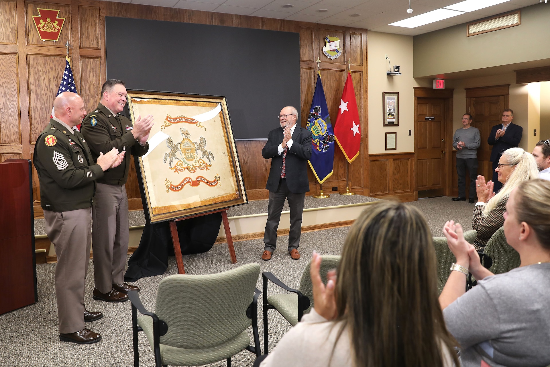 A ceremony marks the return of a historic flag from more than 100 years ago to Pennsylvania National Guard headquarters September 29, 2025, at Fort Indiantown Gap, Pennsylvania. Joseph Reselli, an electrician and lifelong Pennsylvanian who purchased the flag and donated it, presented the flag to Maj. Gen. John R. Pippy, Pennsylvania’s adjutant general, and Command Sgt. Maj. Shawn Phillips, command senior enlisted advisor. It is believed to date from 1920-21, soon after the National Defense Act of 1920 reorganized the U.S. armed forces and formally designated the National Guard, which had previously been known as militias. (U.S. Army National Guard photo by Zane Craig)