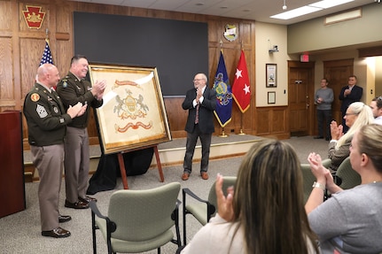 A ceremony marks the return of a historic flag from more than 100 years ago to Pennsylvania National Guard headquarters September 29, 2025, at Fort Indiantown Gap, Pennsylvania. Joseph Reselli, an electrician and lifelong Pennsylvanian who purchased the flag and donated it, presented the flag to Maj. Gen. John R. Pippy, Pennsylvania’s adjutant general, and Command Sgt. Maj. Shawn Phillips, command senior enlisted advisor. It is believed to date from 1920-21, soon after the National Defense Act of 1920 reorganized the U.S. armed forces and formally designated the National Guard, which had previously been known as militias. (U.S. Army National Guard photo by Zane Craig)