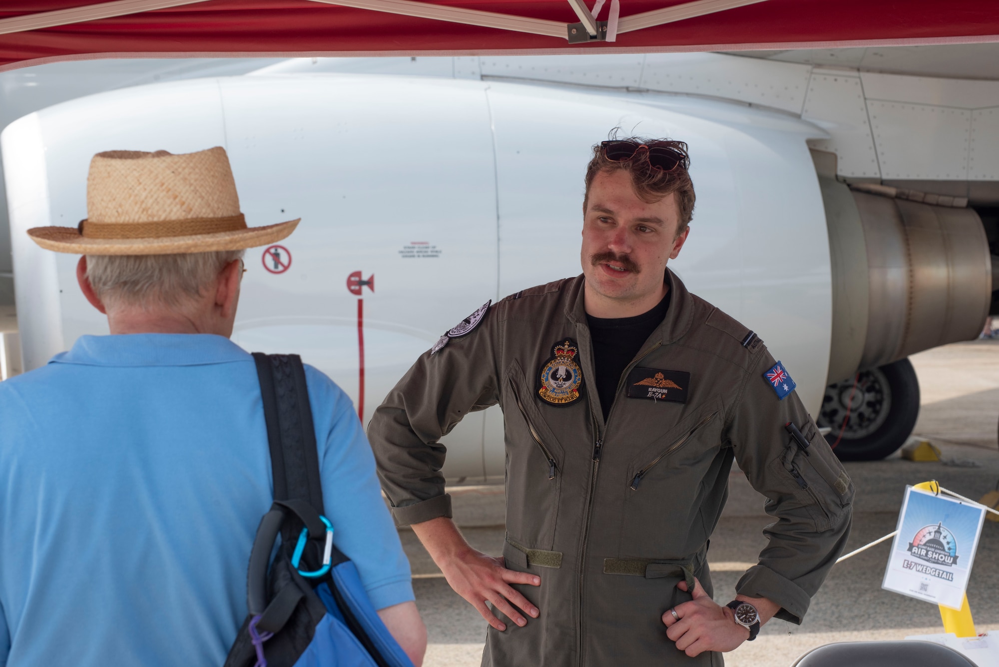 Royal Australian Air Force Flying Officer Harvey Steele, an E-7A Wedgetail aircraft crew member, speaks to a visitor at the Joint Base Andrews Air Show at Joint Base Andrews, Maryland, Sept. 14, 2025. The Australian aircrew was in the middle of an integration exercise with U.S. Air Force and Navy units on the West Coast and flew to Andrews to support the air show.
