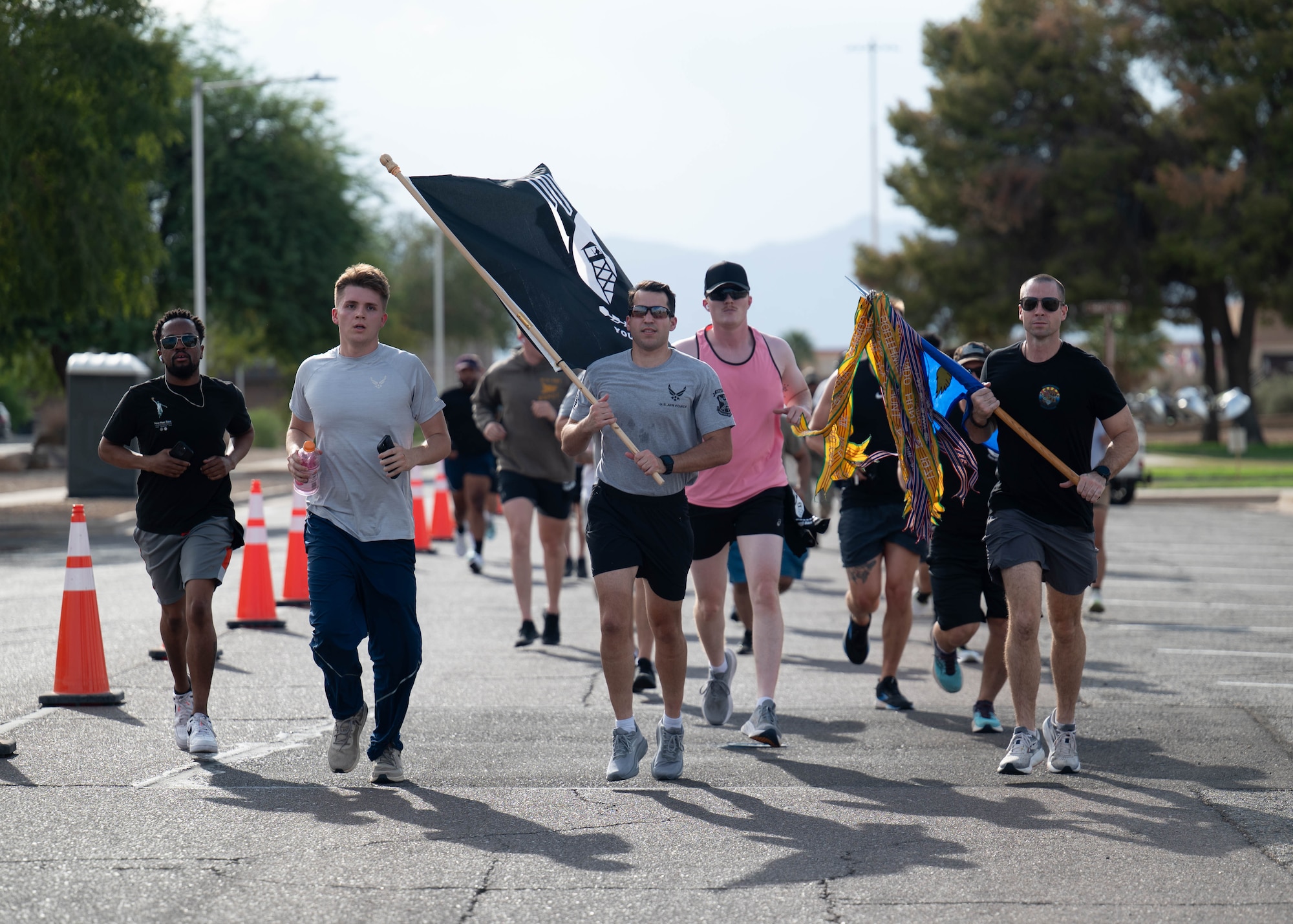 U.S. Air Force Airmen assigned to the 56th Fighter Wing carry a POW/MIA flag and squadron guidons while running laps during the 24-hour POW/MIA remembrance run, Sept. 18, 2025, at Luke Air Force Base, Arizona. The event honors prisoners of war and those missing in action, ensuring their sacrifice is never forgotten. Runners kept the POW/MIA flag moving for a full day to show America’s resolve to bring every service member home. (U.S. Air Force photo by Airman Rebecca Wagner)