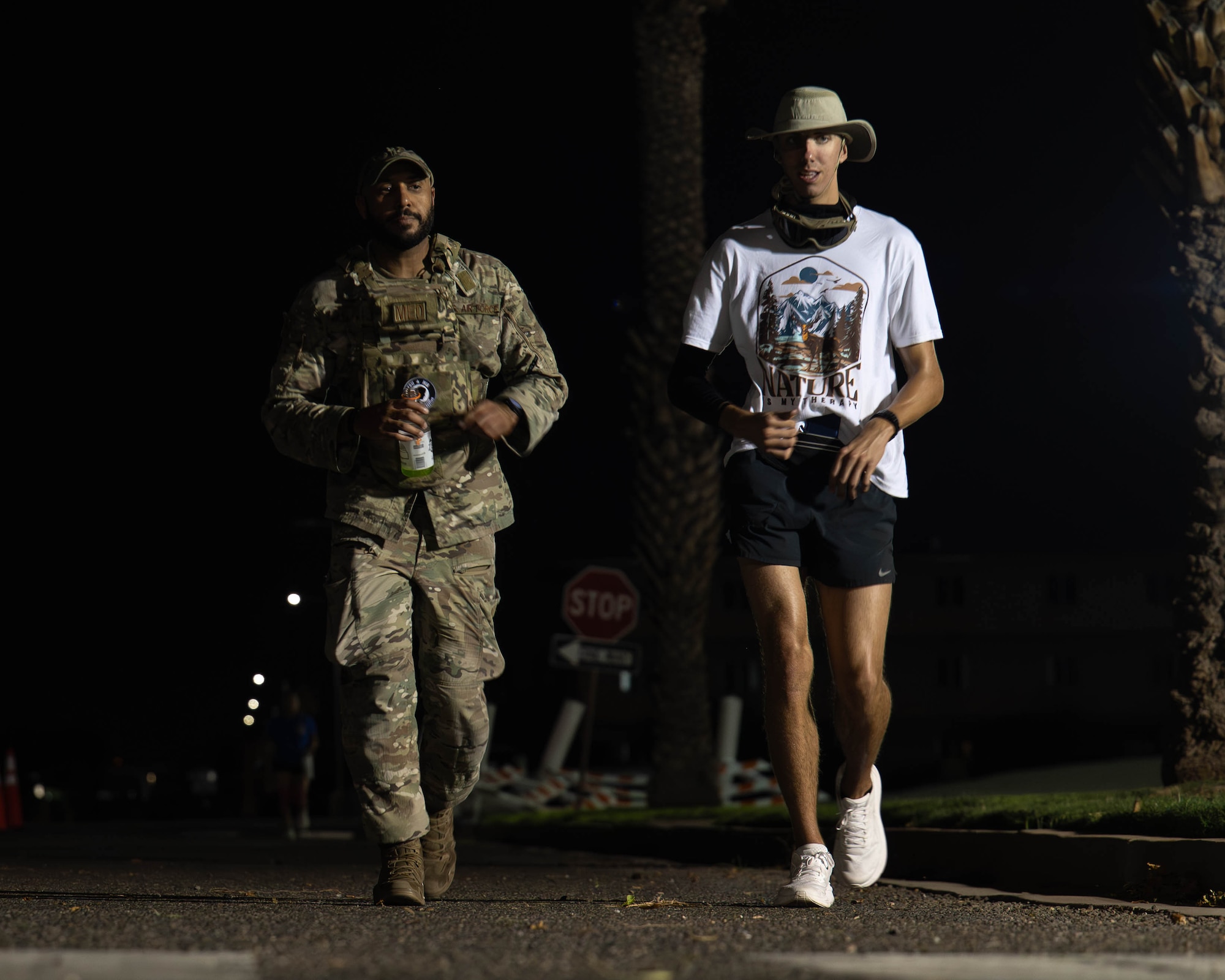U.S. Air Force Staff Sgt. Ricardo Brown (left), 56th Operational Medical Readiness Squadron community health noncommissioned officer in charge, and Airman 1st Class Thomas Gordon (right), 310th Aircraft Maintenance Unit crew chief, walk side-by-side during the overnight portion of the 24-hour POW/MIA remembrance run, Sept. 18, 2025, at Luke Air Force Base, Arizona. Brown and Gordon participated in the run for the entire 24-hour period. At the end of the run both Airmen were recognized for their dedication through the presentation of a coin; they exemplify the spirit of resilience and warrior ethos that is the standard. (U.S. Air Force photo by Airman Rebecca Wagner)