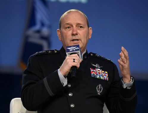 A military general speaks in to a microphone at a conference.