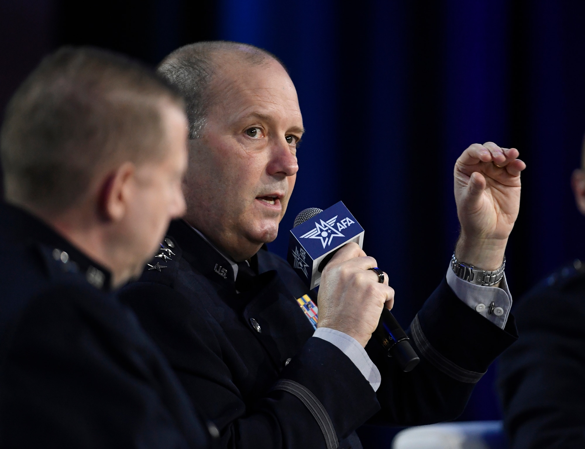 A military general speaks in to a microphone at a conference.