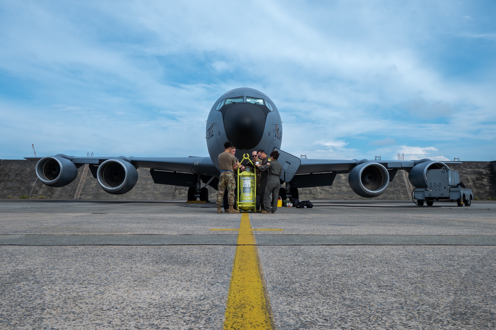 front view of a KC-135 from the nose and the aircrew meeting underneath it