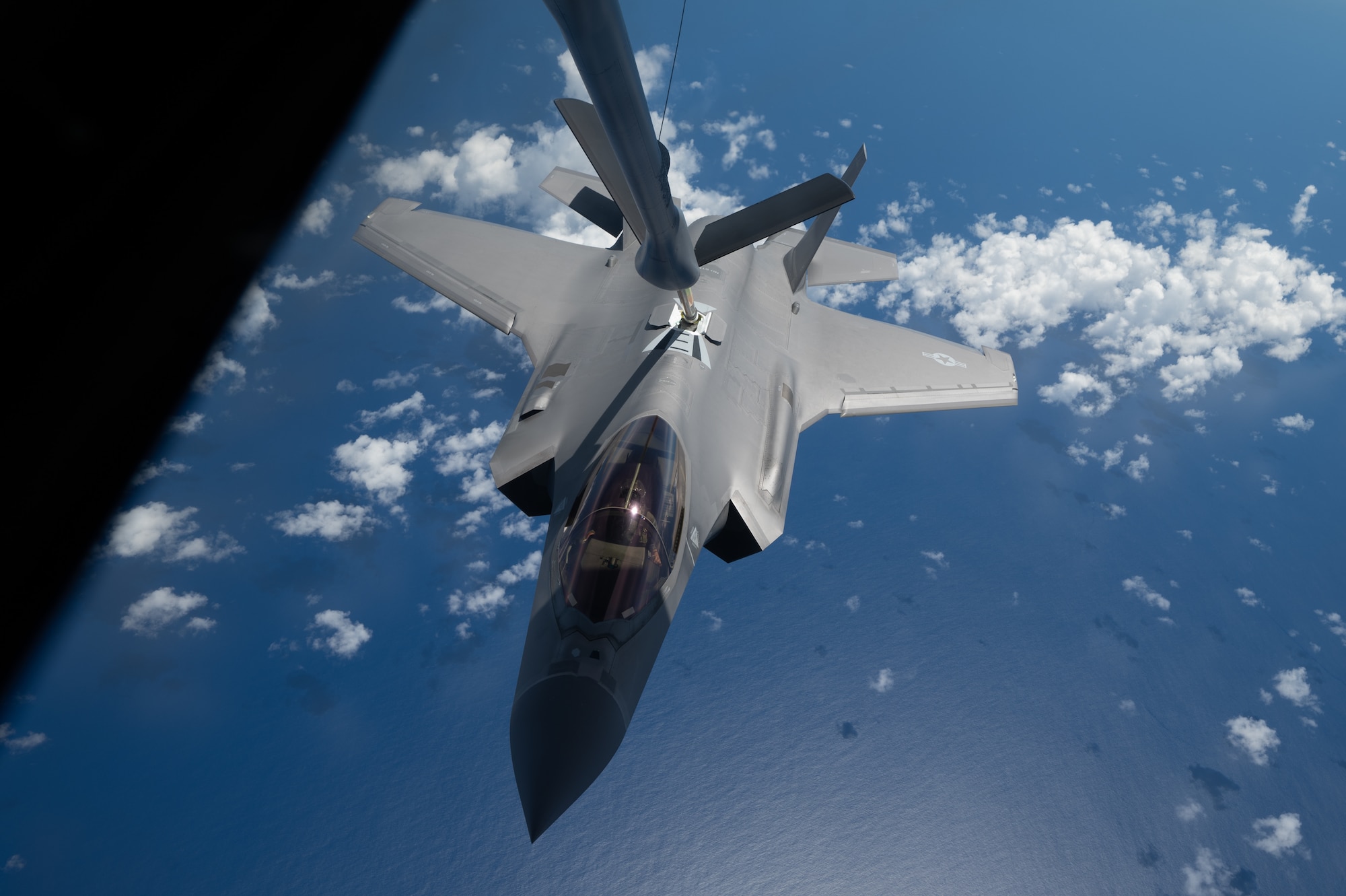 A F-35 jet flies underneath a KC-135 and gets refueled