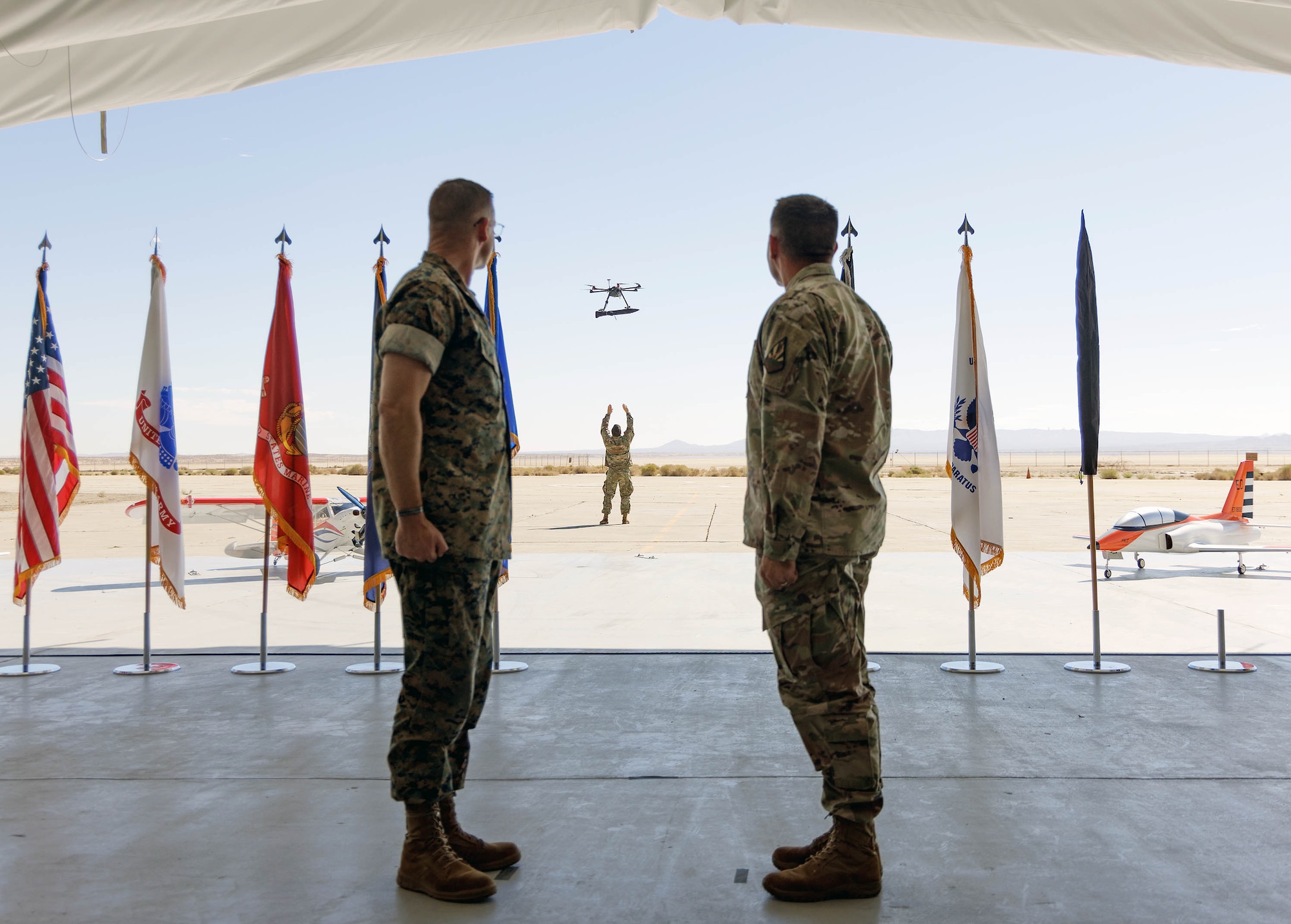 Two military officers watch a drone deliver the unit colors during US-X’s establishment ceremony.