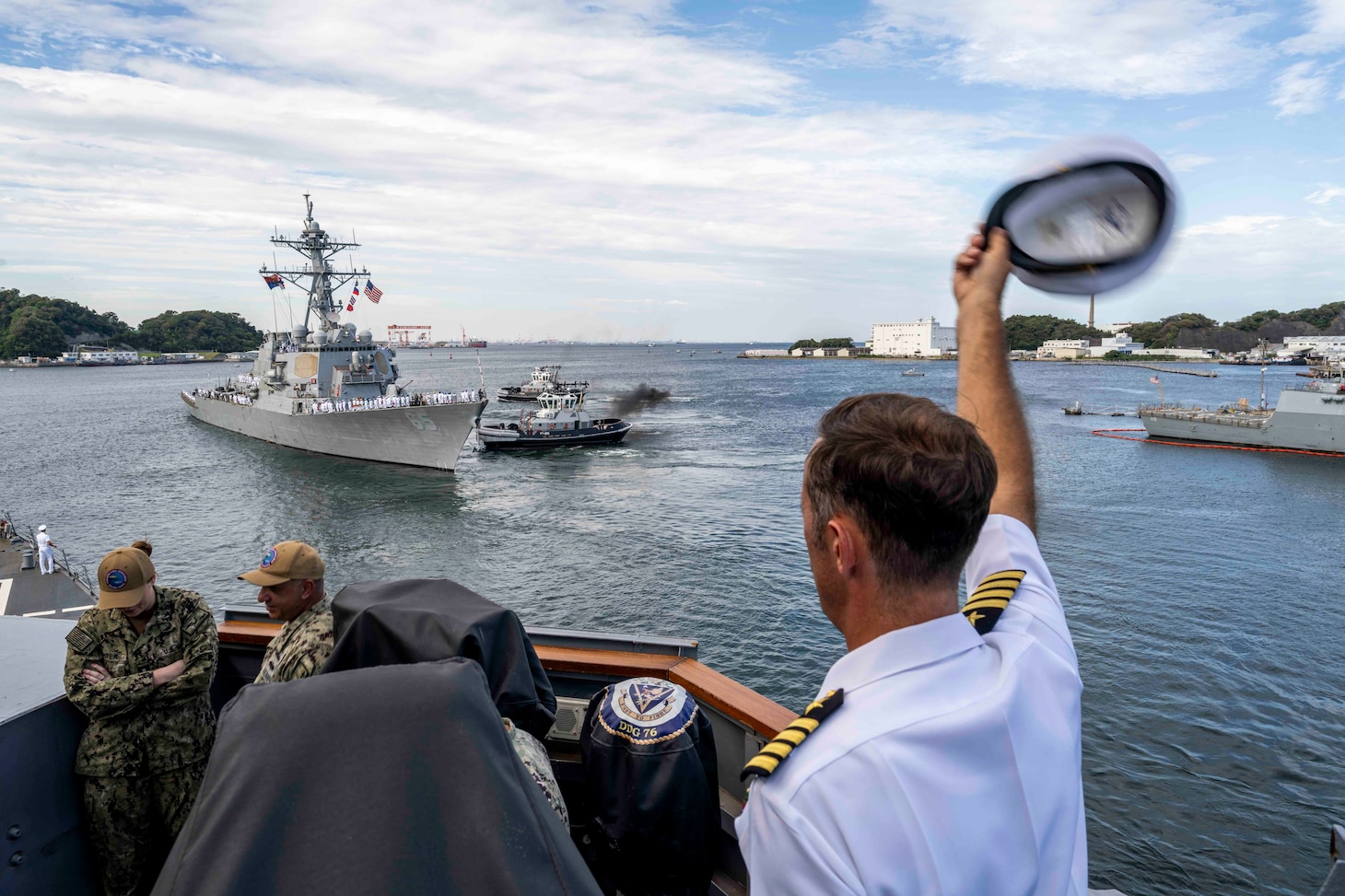 Capt. David Huljack, commanding officer of Commander, Destroyer Squadron 15, waves farewell to the crew of the Arleigh Burke-class guided-missile destroyer USS Benfold (DDG 65) from the starboard bridge wing of the Arleigh Burke-class guided-missile destroyer USS Higgins (DDG 76) as Benfold departs Commander, Fleet Activities Yokosuka, Japan, Sept. 29, following 10 consecutive years of forward-deployed service in the U.S. 7th Fleet area of operations.