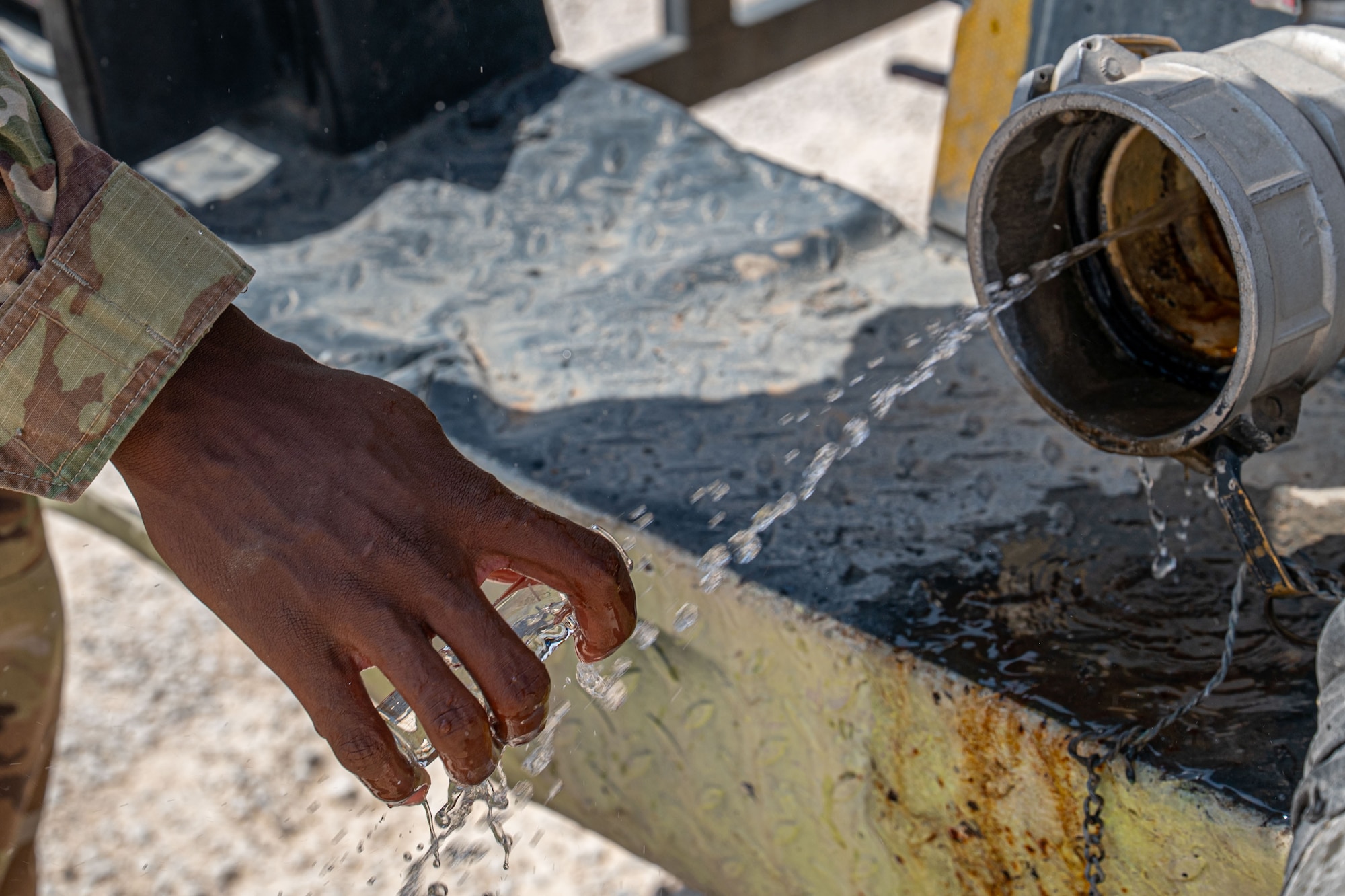 U.S. Air Force Senior Airman Daniel Kapsetta, 378th Expeditionary Civil Engineer Squadron water and fuel systems maintenance journeyman, collects a water sample from a delivery truck.