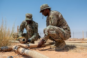 U.S. Air Force Senior Airman Daniel Kapsetta, 378th Expeditionary Civil Engineer Squadron water and fuel systems maintenance journeyman, and Staff Sgt. Abdul Guira, 378th ECES water and fuel systems maintenance craftsman, connect a water line.