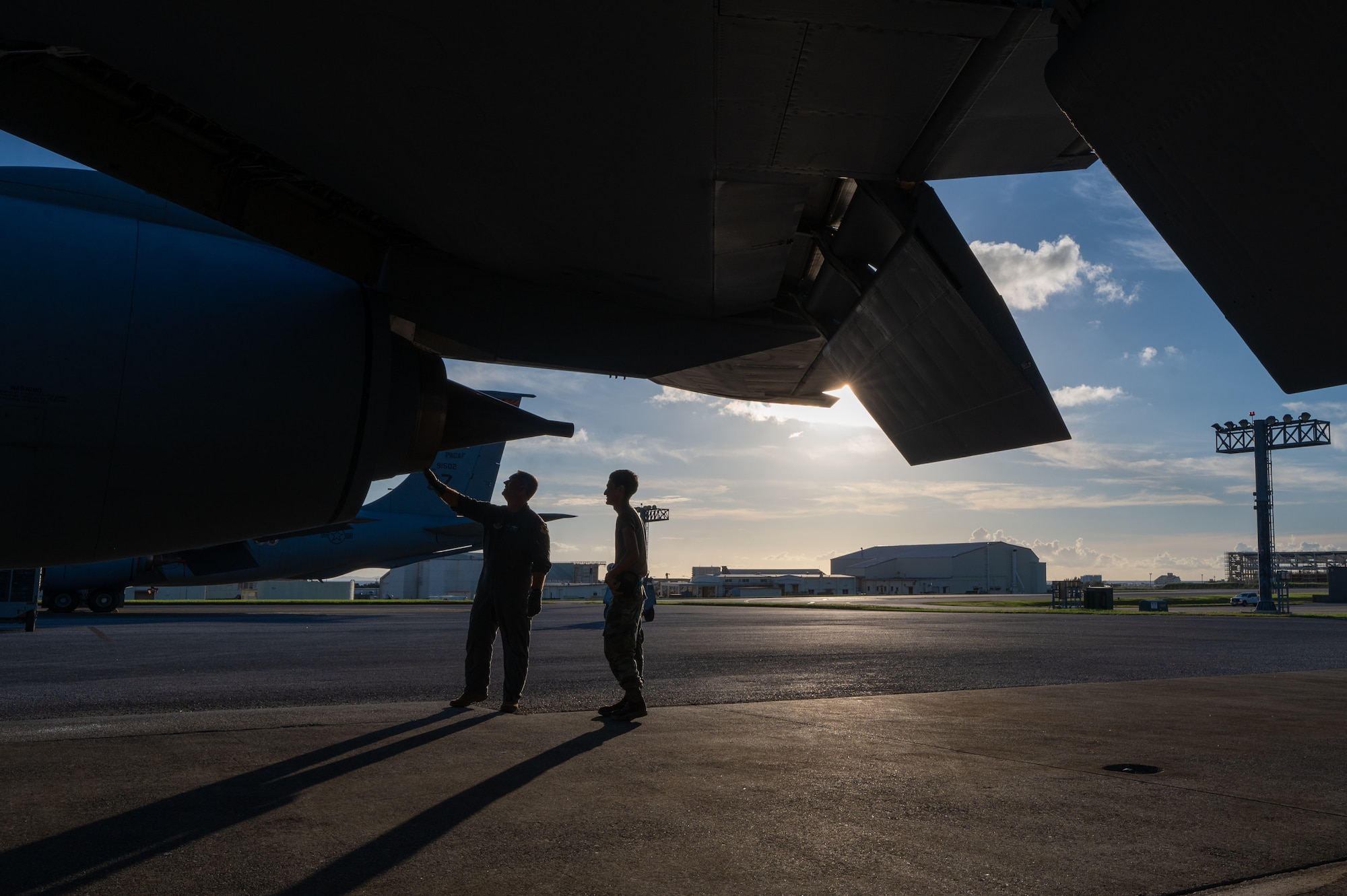 two military members walk underneath a KC-135 shadowed