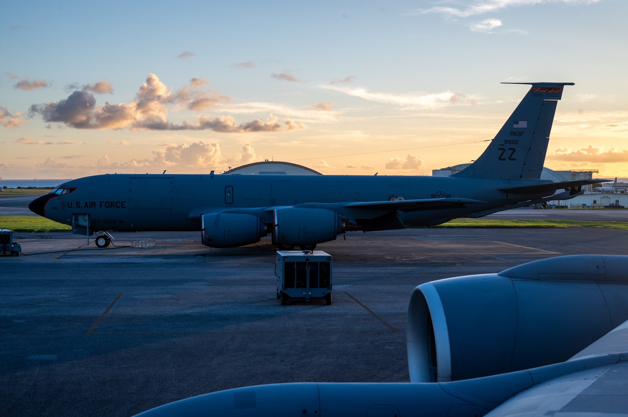 a side view of a KC-135 parked with a sunset in the background