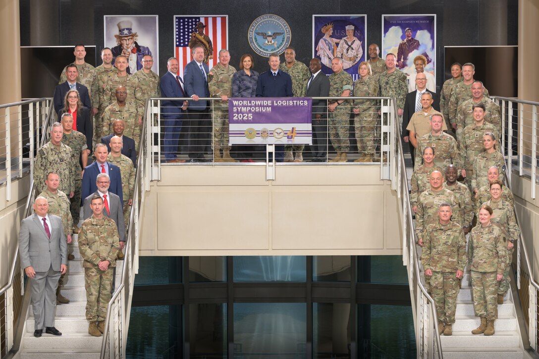 Worldwide Logistics Symposium participants are posed for a group photo across two staircases