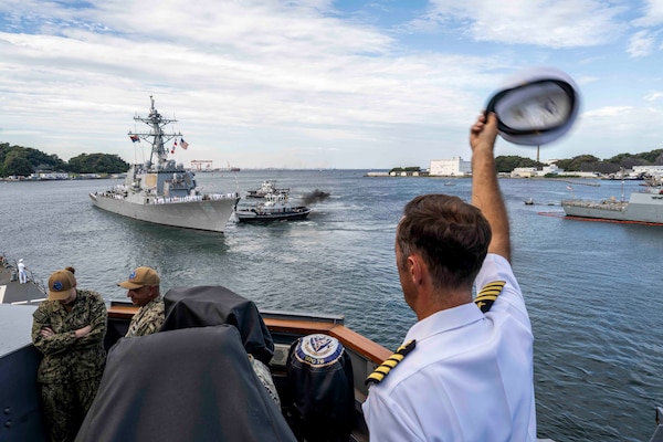 Capt. David Huljack, commanding officer of Commander, Destroyer Squadron 15, waves farewell to the crew of the Arleigh Burke-class guided-missile destroyer USS Benfold (DDG 65) from the starboard bridge wing of the Arleigh Burke-class guided-missile destroyer USS Higgins (DDG 76) as Benfold departs Commander, Fleet Activities Yokosuka, Japan, Sept. 29, following 10 consecutive years of forward-deployed service in the U.S. 7th Fleet area of operations.
