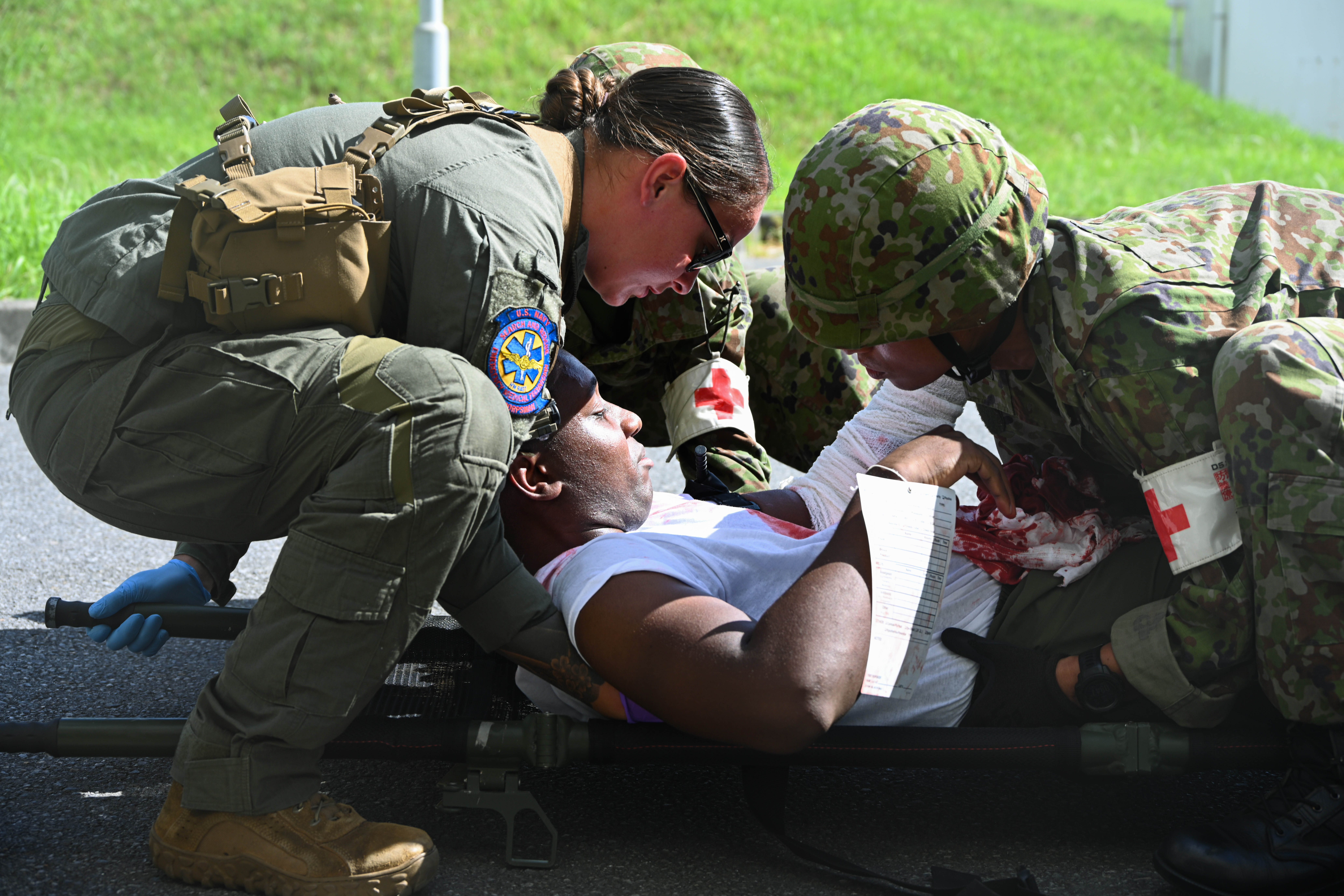 U.S. Navy Hospital Corpsman 2nd Class Kristin Cove, left, a search and rescue medical technician with 3rd Medical Battalion, 3rd Marine Logistics Group, and Japan Ground Self-Defense Force medical personnel transport a simulated casualty during bilateral mass casualty training as part of Resolute Dragon 25 at Camp Naha, Okinawa, Japan, Sept. 19, 2025. Resolute Dragon is an annual bilateral exercise across Japan, including the Southwest Islands, that strengthens the command, control and multi-domain maneuver capabilities of III MEF and the Japan Ground Self-Defense Force’s Western Army personnel, alongside representatives across the U.S. and Japanese Joint Force, with a focus on controlling and defending key maritime terrain. Cove is a native of California. (U.S. Marine Corps photo by Lance Cpl. Rachel Mason)
