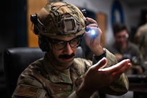 A Airman checks to see if his flashlight works by shining it on his hand.