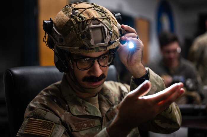 A Airman checks to see if his flashlight works by shining it on his hand.