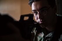An Airman stares the down the rifle of a practice M4 rifle.