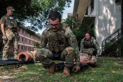 Two Airmen practice litter techniques on a Self Aid Buddy care dummy.