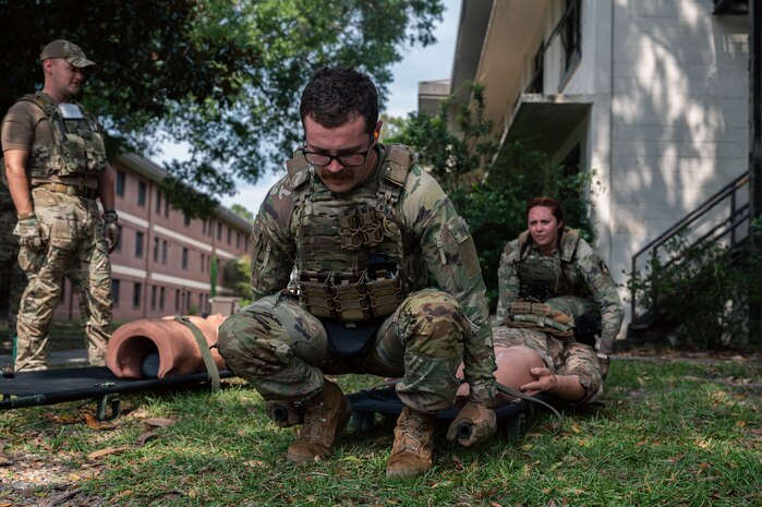 Two Airmen practice litter techniques on a Self Aid Buddy care dummy.