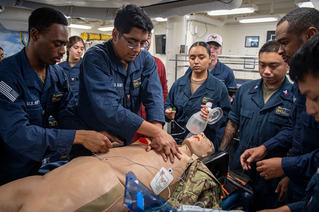 250830-N-AM483-2049 U.S. CENTRAL COMMAND AREA OF RESPONSIBILITY (Aug. 30, 2025) U.S. Sailors work together to save an emergency medical practice dummy during stretcher bearer training on the mess deck of the Arleigh Burke-class guided-missile destroyer USS Lenah Sutcliffe Higbee (DDG 123) in the U.S. Central Command area of responsibility. (Official U.S. Navy photo) (Photo has been edited by blurring sensitive material)