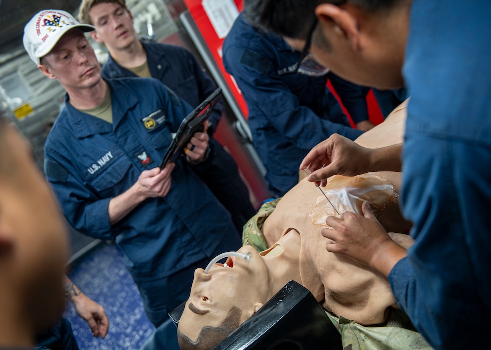 250830-N-AM483-2020 U.S. CENTRAL COMMAND AREA OF RESPONSIBILITY (Aug. 30, 2025) A U.S. Navy Hospital Corpsman monitors stretcher bearer training on the mess deck of the Arleigh Burke-class guided-missile destroyer USS Lenah Sutcliffe Higbee (DDG 123) in the U.S. Central Command area of responsibility. (Official U.S. Navy photo)