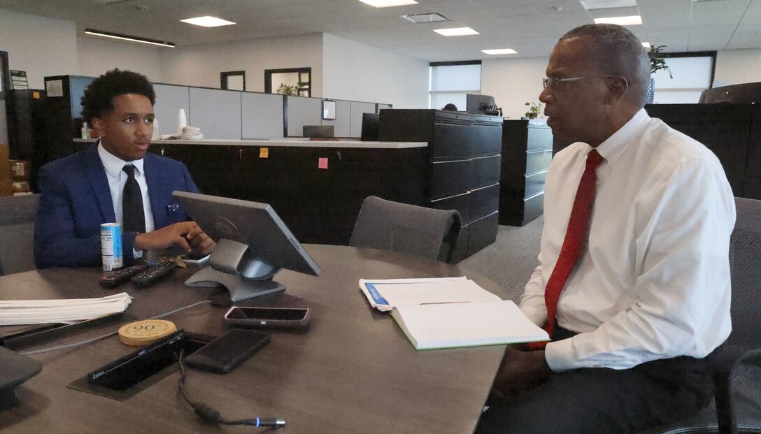 A Man and a young man sitting at a table talking.