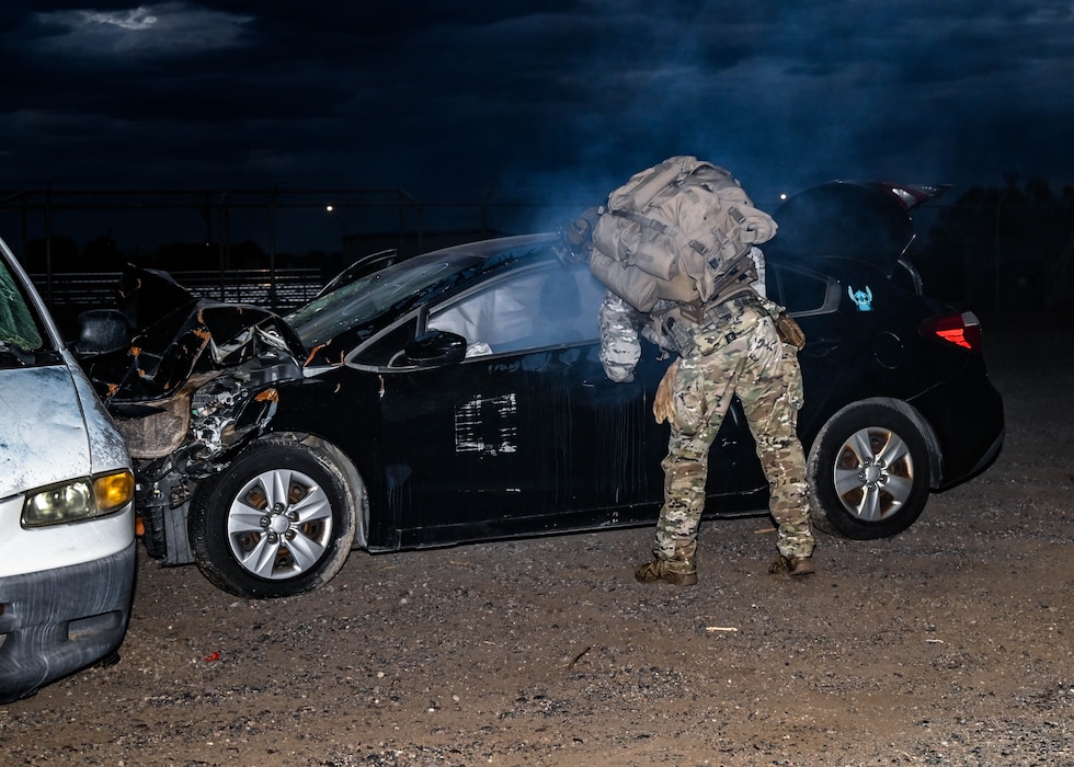 U.S. Air Force Senior Airman Kevin Hodgson, 56th Civil Engineer Squadron Explosive Ordnance Disposal technician, views the interior of a smoking vehicle during an Ability to Survive and Operate overnight field exercise