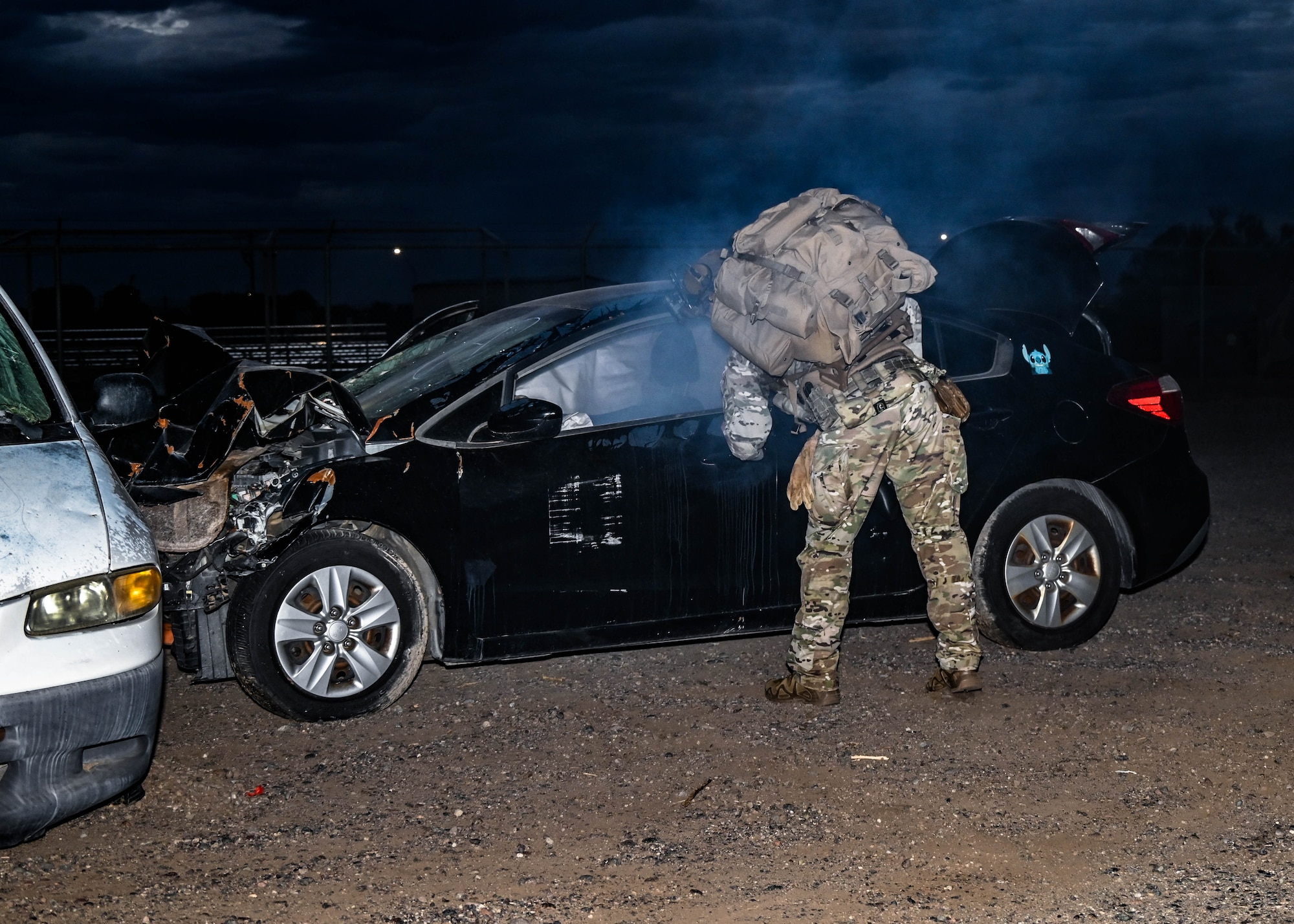 U.S. Air Force Senior Airman Kevin Hodgson, 56th Civil Engineer Squadron Explosive Ordnance Disposal technician, views the interior of a smoking vehicle during an Ability to Survive and Operate overnight field exercise