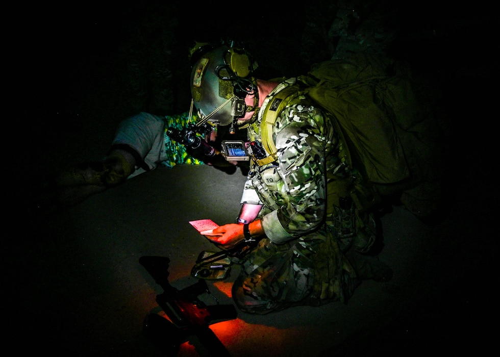 U.S. Air Force Senior Airman Kevin Hodgson, 56th Civil Engineer Squadron Explosive Ordnance Disposal technician, reviews tactical notes under night vision conditions during an Ability to Survive and Operate overnight field exercise