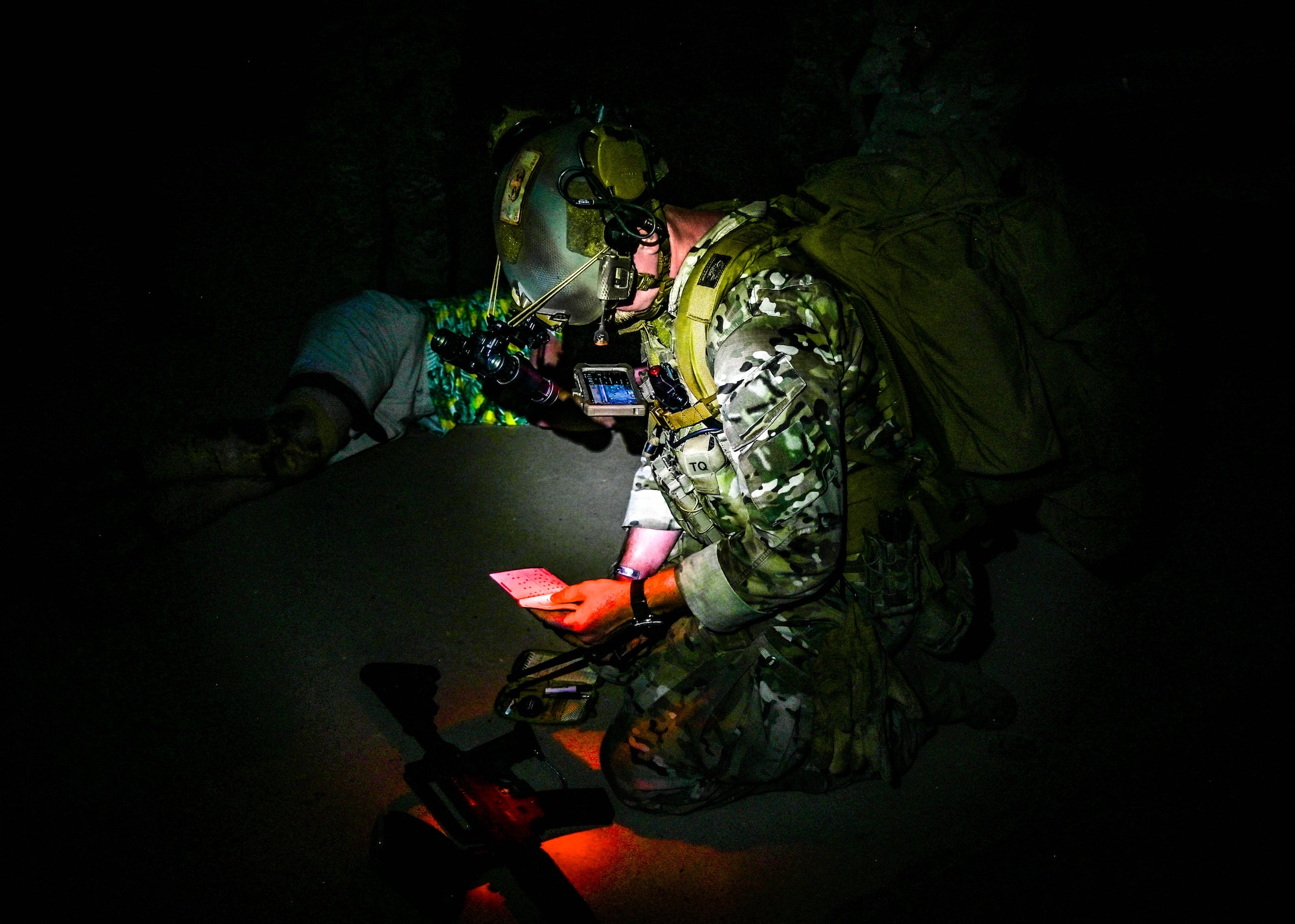 U.S. Air Force Senior Airman Kevin Hodgson, 56th Civil Engineer Squadron Explosive Ordnance Disposal technician, reviews tactical notes under night vision conditions during an Ability to Survive and Operate overnight field exercise