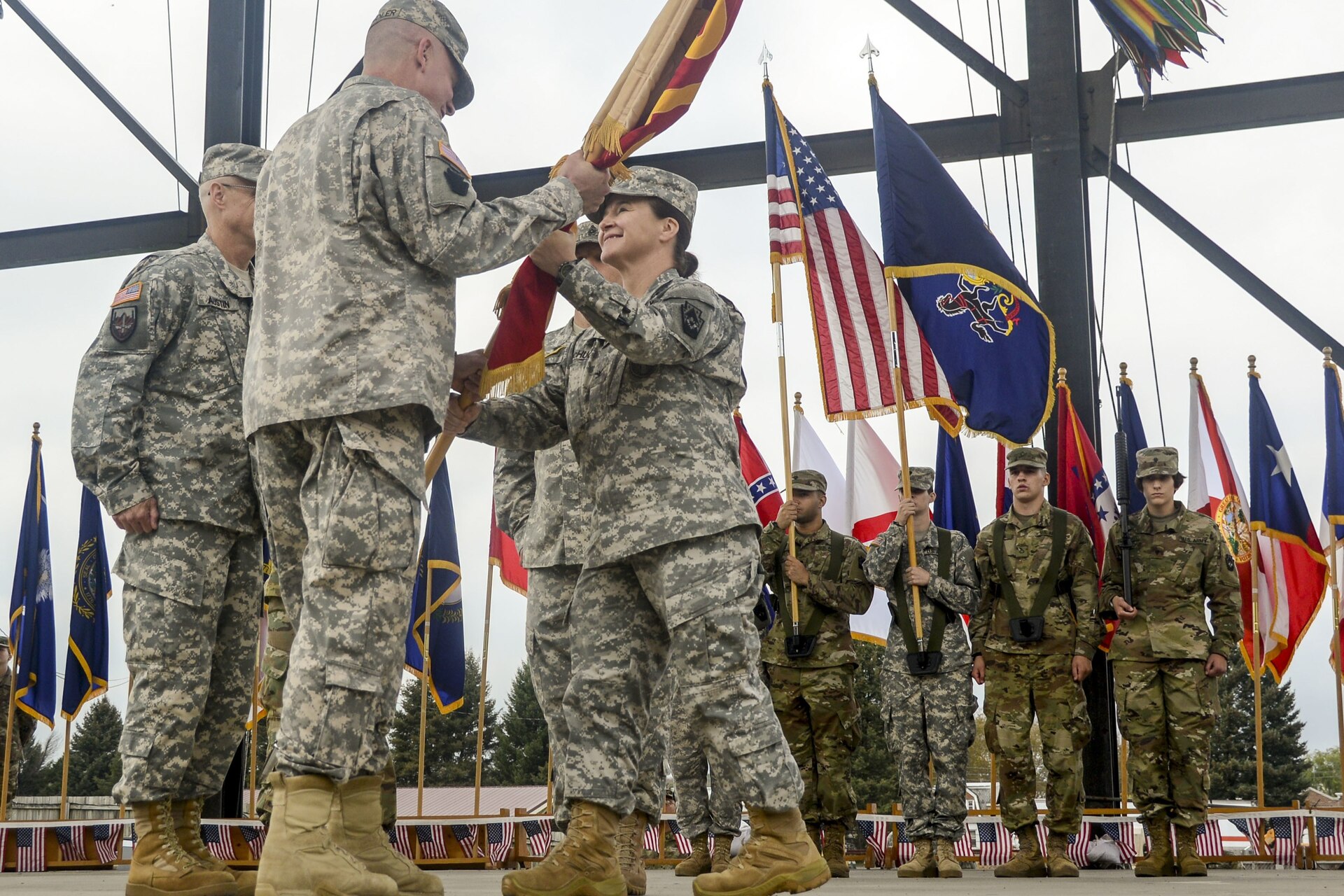 Then-Col. Laura McHugh, outgoing commander of the 213th Regional Support Group, Pennsylvania Army National Guard, passes the group colors to Then-Col. Mark Schindler, deputy adjutant general - Army, during the unit’s change of command ceremony Oct. 15, 2017, at the Allentown Fairgrounds. (U.S. Army National Guard photo by Sgt. Zane Craig)