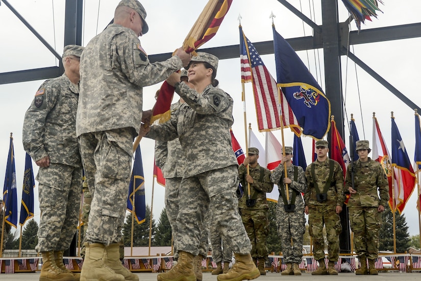 Then-Col. Laura McHugh, outgoing commander of the 213th Regional Support Group, Pennsylvania Army National Guard, passes the group colors to Then-Col. Mark Schindler, deputy adjutant general - Army, during the unit’s change of command ceremony Oct. 15, 2017, at the Allentown Fairgrounds. (U.S. Army National Guard photo by Sgt. Zane Craig)