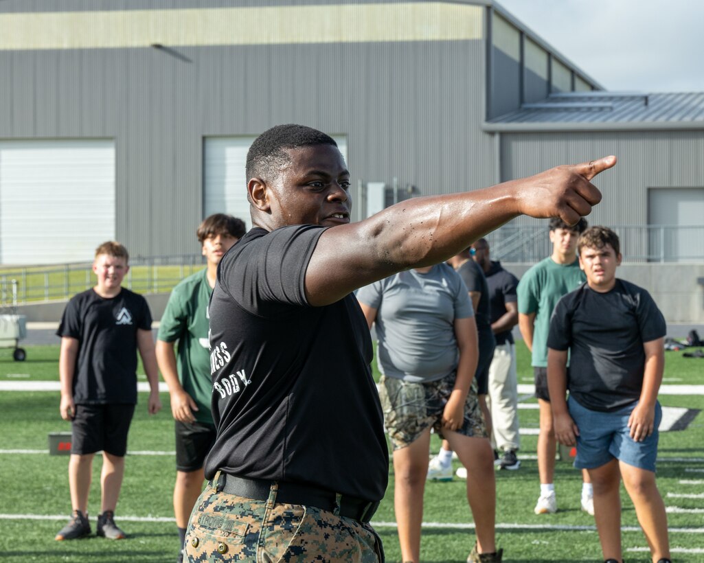 U.S. Marine Corps Sgt. Oscar Strong, a recruiter with Recruiting Sub-Station Round Rock, Recruiting Station Austin, speaks to Taylor High School students during a Marine physical training session at Taylor High School in Austin, Texas, July 24, 2025. Marine physical training sessions are conducted to engage with high school football teams in exclusive training opportunities alongside U.S. Marines, enriching the cohesion within participating teams. (U.S. Marine Corps photo by Sgt. Jose D. Cruz)