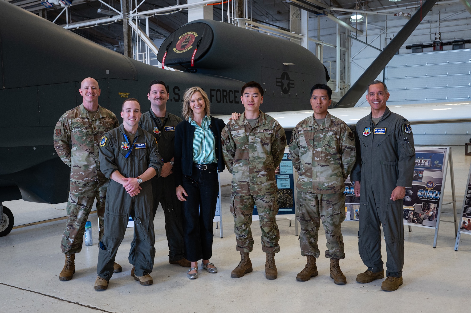 A photo of a group of people standing together in front of a plane in an airplane hangar.